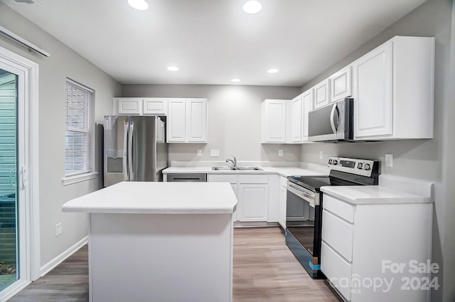 kitchen with white cabinets, appliances with stainless steel finishes, a center island, and a healthy amount of sunlight