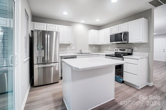 kitchen with white cabinetry, sink, a center island, stainless steel appliances, and light hardwood / wood-style flooring