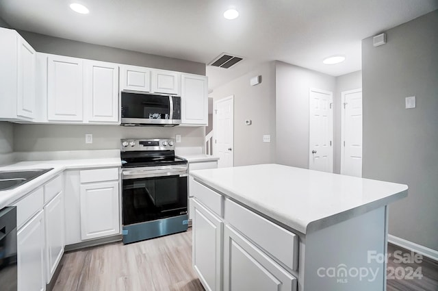 kitchen with sink, a kitchen island, light hardwood / wood-style floors, white cabinets, and appliances with stainless steel finishes