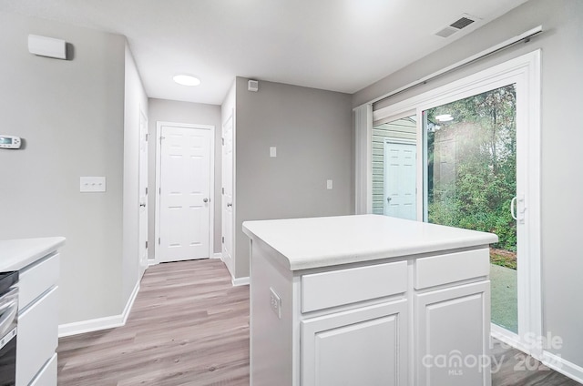 kitchen featuring white cabinets, light hardwood / wood-style floors, stainless steel range oven, and a kitchen island