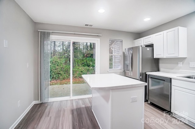 kitchen with white cabinetry, dishwasher, a kitchen island, and light hardwood / wood-style flooring