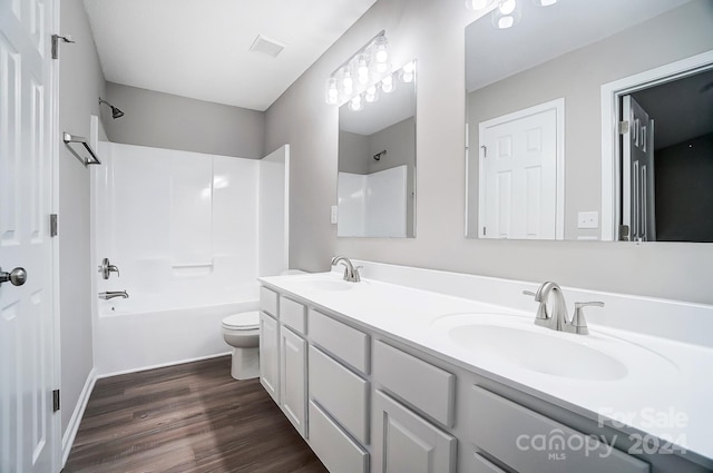 full bathroom featuring washtub / shower combination, hardwood / wood-style floors, vanity, and toilet