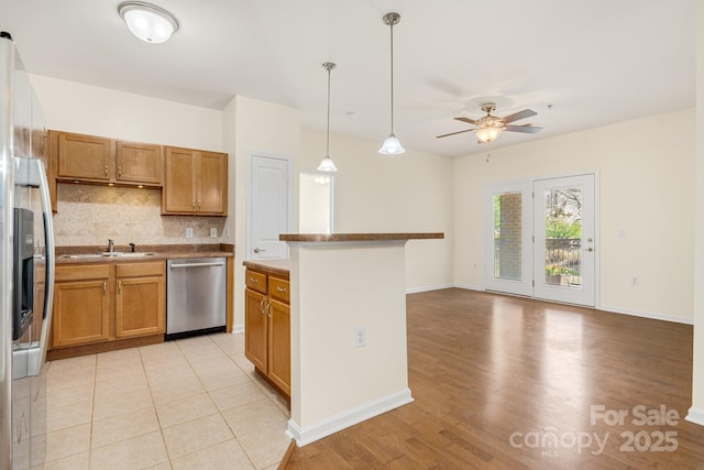 kitchen featuring ceiling fan, stainless steel appliances, tasteful backsplash, pendant lighting, and a kitchen island