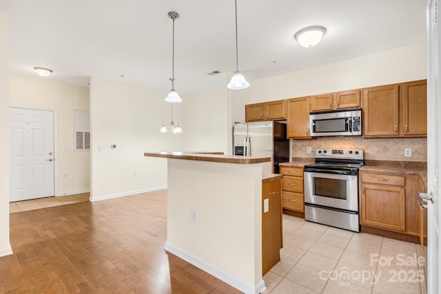 kitchen with backsplash, stainless steel appliances, light tile patterned floors, a center island, and hanging light fixtures