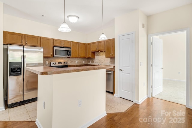 kitchen with hanging light fixtures, decorative backsplash, light wood-type flooring, a kitchen island, and stainless steel appliances