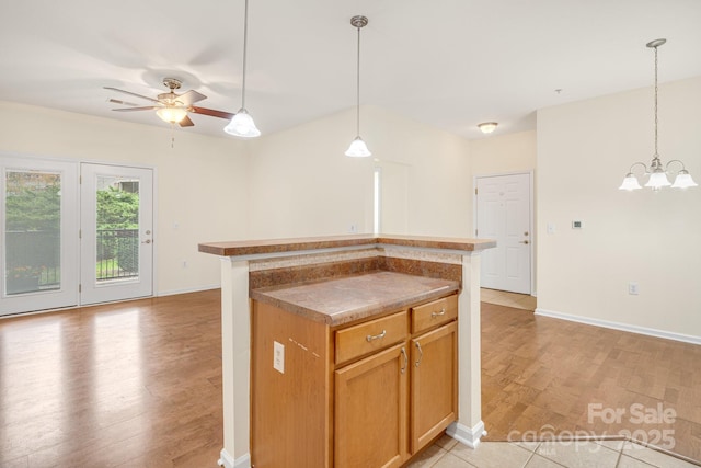 kitchen with ceiling fan with notable chandelier, a center island, light wood-type flooring, and decorative light fixtures