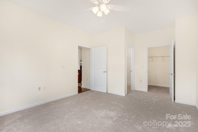 unfurnished bedroom featuring ceiling fan, a closet, light colored carpet, and a spacious closet