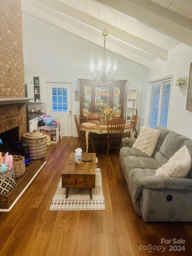 living room featuring a chandelier, wood-type flooring, vaulted ceiling with beams, and a fireplace