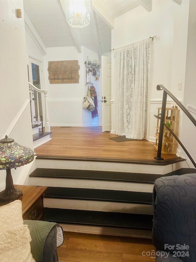 stairway featuring hardwood / wood-style floors and vaulted ceiling with beams