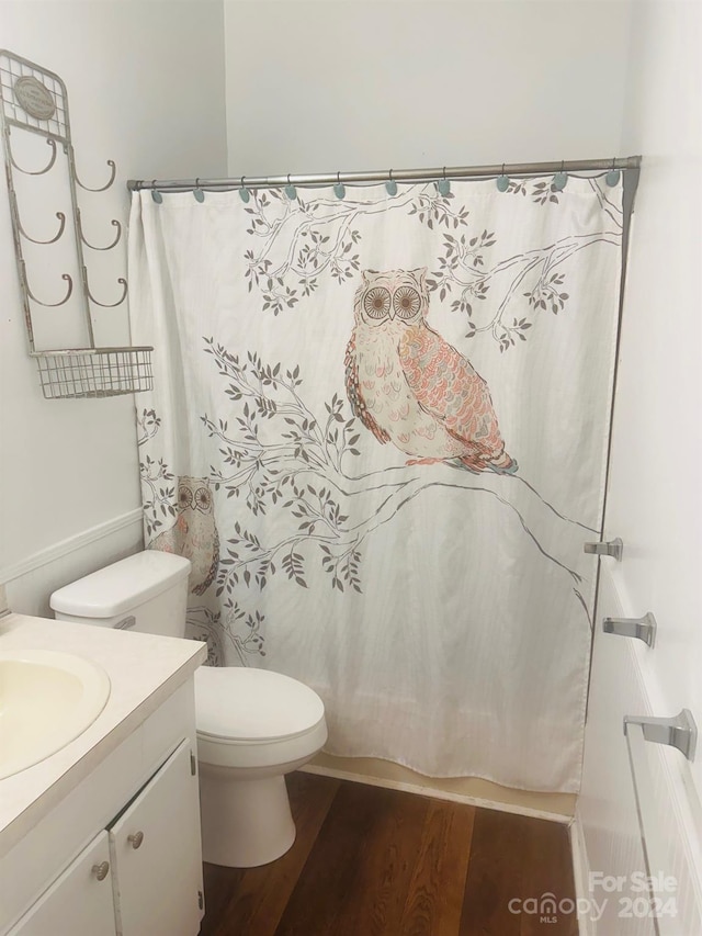 bathroom with toilet, vanity, wood-type flooring, and curtained shower