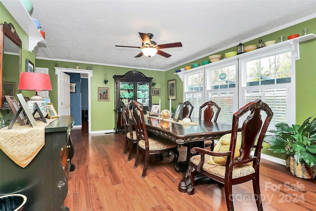 dining space with a textured ceiling, wood-type flooring, ceiling fan, and crown molding