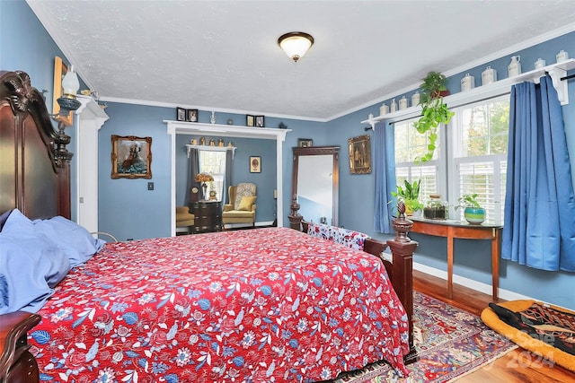 bedroom with a textured ceiling, hardwood / wood-style flooring, and ornamental molding