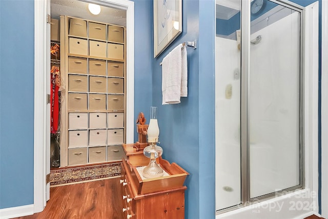 bathroom with hardwood / wood-style floors and a shower with shower door