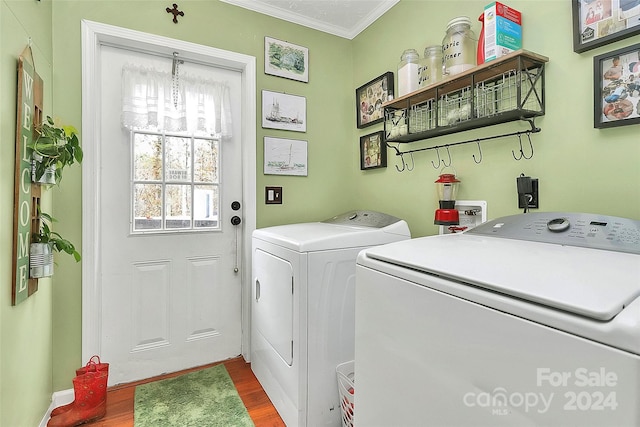 washroom with washing machine and dryer, a notable chandelier, crown molding, and hardwood / wood-style flooring