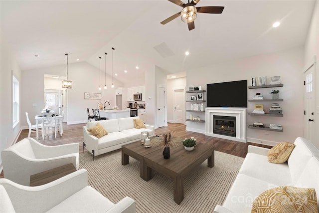 living room with hardwood / wood-style floors, ceiling fan, sink, and vaulted ceiling