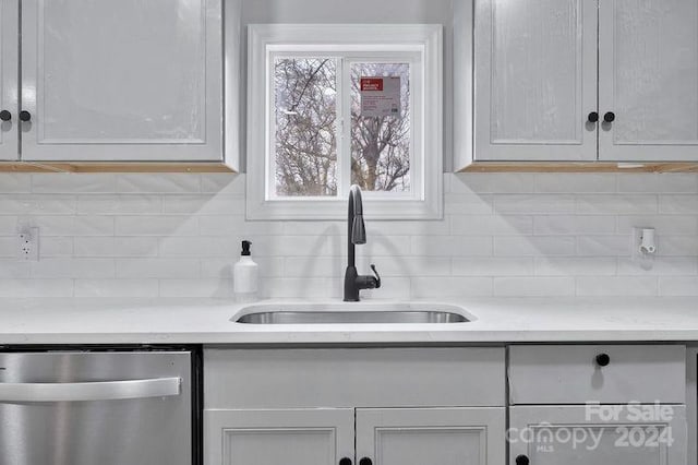 kitchen with stainless steel dishwasher, a healthy amount of sunlight, sink, and tasteful backsplash