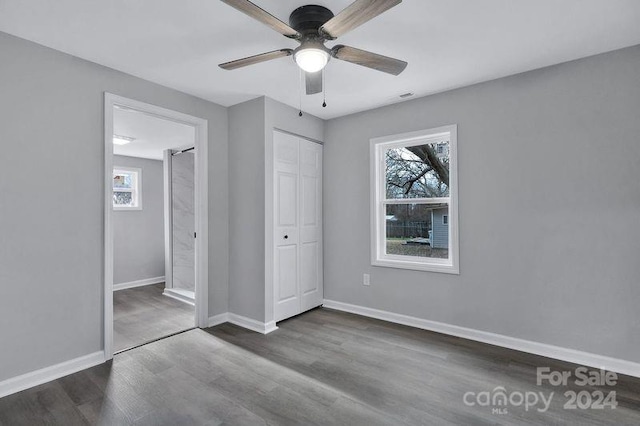 unfurnished bedroom featuring multiple windows, a closet, ceiling fan, and dark wood-type flooring