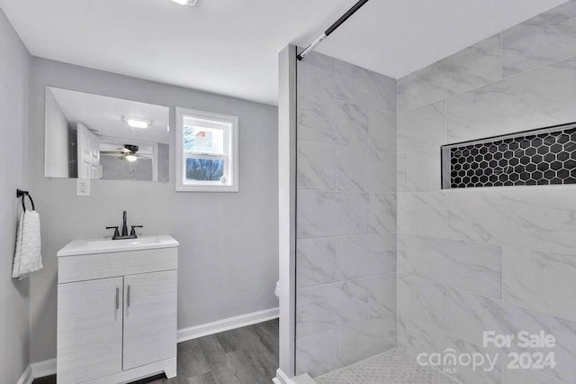 bathroom with vanity, ceiling fan, wood-type flooring, and tiled shower