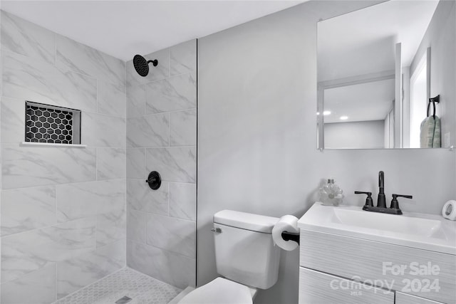 bathroom with vanity, toilet, and a tile shower