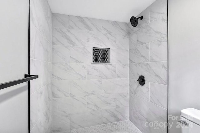 bathroom featuring tiled shower and toilet