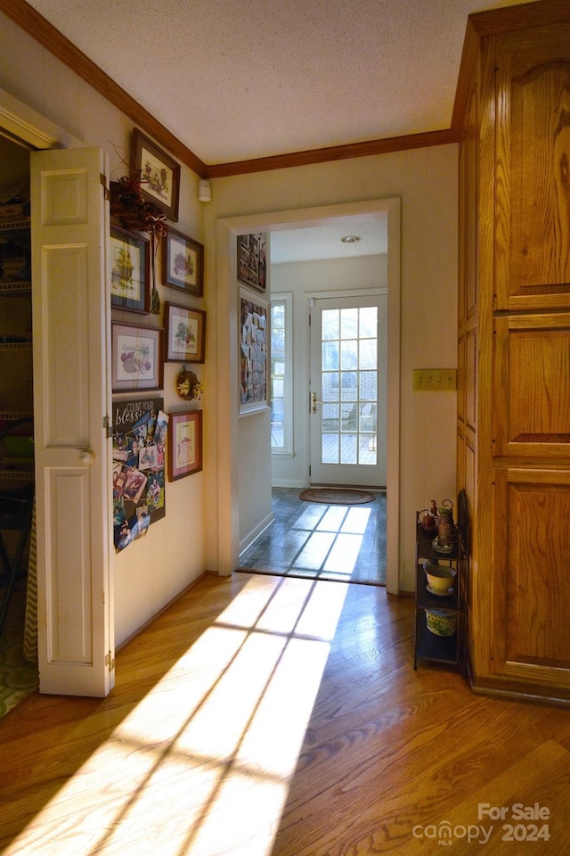 entryway featuring a textured ceiling, light hardwood / wood-style flooring, and crown molding