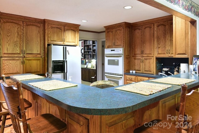 kitchen featuring a breakfast bar, white appliances, and ornamental molding