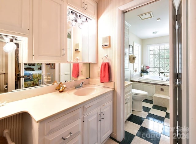 bathroom featuring tiled tub, vanity, and toilet