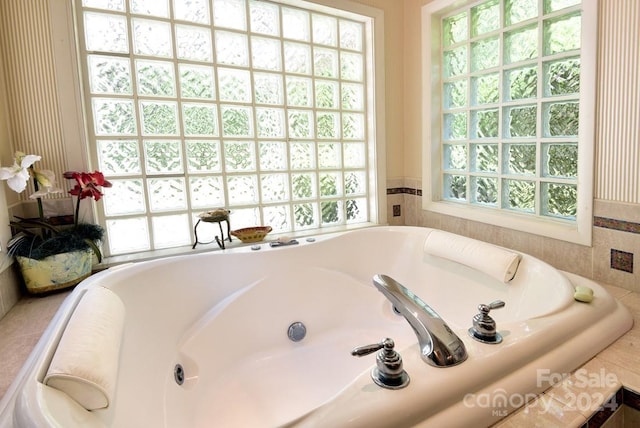 bathroom with a tub to relax in and a healthy amount of sunlight