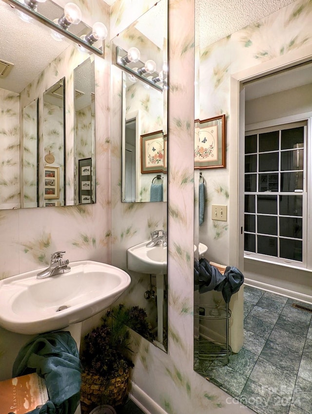 bathroom featuring dual sinks and a textured ceiling