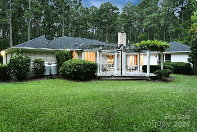 back of property featuring a pergola, a deck, and a lawn