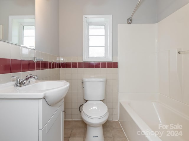 full bathroom featuring toilet, tile patterned floors, a wealth of natural light, and tile walls