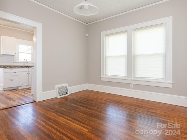 interior space with ornamental molding, a textured ceiling, and dark wood-type flooring