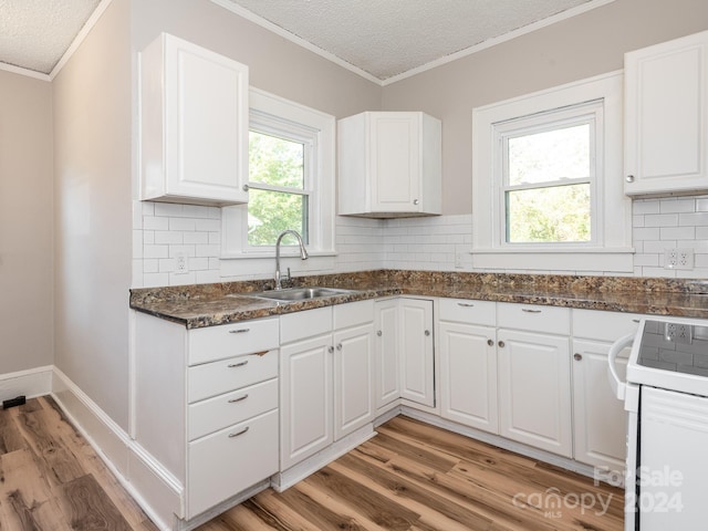 kitchen with white cabinets, light hardwood / wood-style floors, sink, and white stove