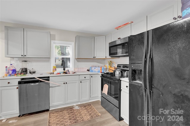 kitchen featuring white cabinetry, sink, tasteful backsplash, light hardwood / wood-style flooring, and black appliances