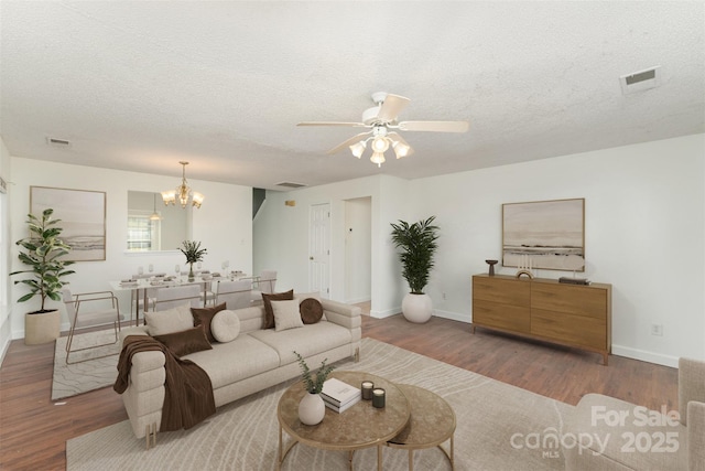 living room with wood-type flooring, ceiling fan with notable chandelier, and a textured ceiling