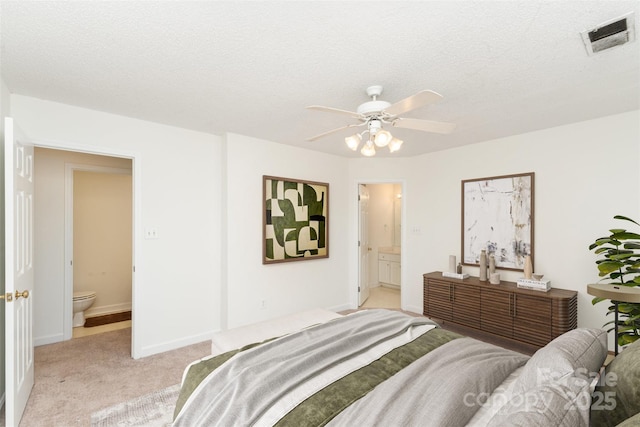 carpeted bedroom featuring ceiling fan, a textured ceiling, and ensuite bath