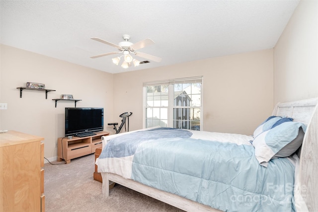 bedroom with ceiling fan, light colored carpet, and a textured ceiling