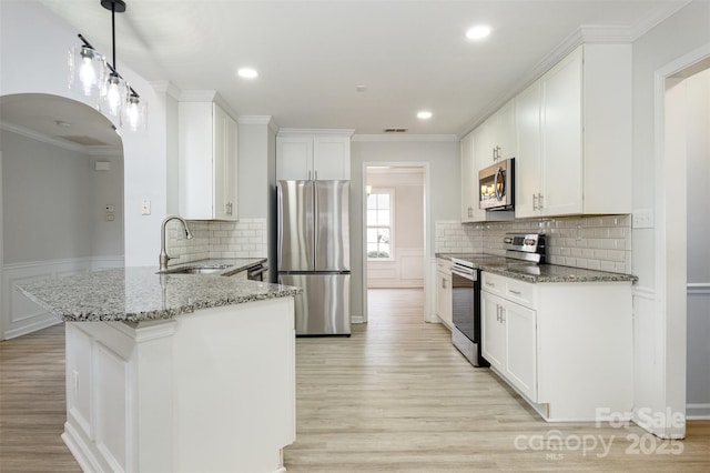 kitchen with sink, white cabinets, kitchen peninsula, stainless steel appliances, and light stone countertops