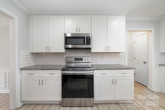 kitchen featuring stainless steel appliances, white cabinetry, stone counters, and light hardwood / wood-style flooring