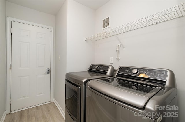 laundry area with washer and clothes dryer and light hardwood / wood-style flooring