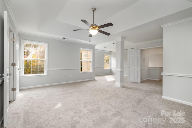 unfurnished bedroom with ornate columns, ornamental molding, ceiling fan, a raised ceiling, and light carpet