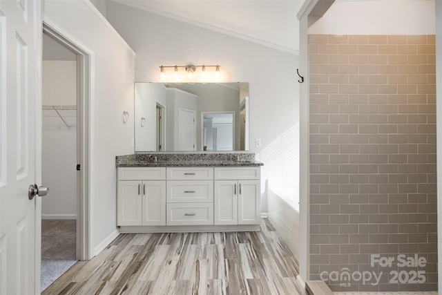 bathroom with crown molding, a bathtub, vanity, wood-type flooring, and vaulted ceiling