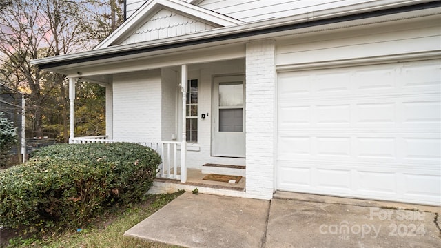 view of exterior entry featuring a porch and a garage