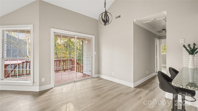 dining space with vaulted ceiling, light hardwood / wood-style floors, a chandelier, and a healthy amount of sunlight