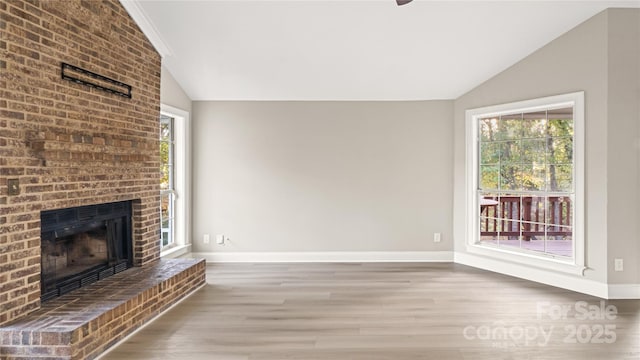 unfurnished living room with lofted ceiling, a fireplace, and hardwood / wood-style floors