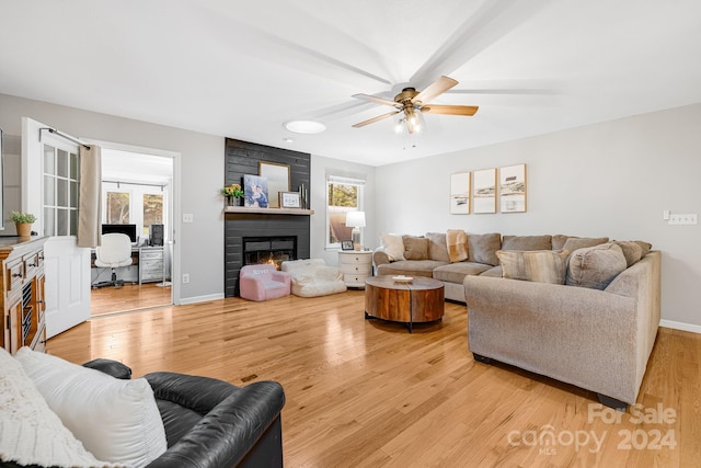 living room with a large fireplace, plenty of natural light, hardwood / wood-style flooring, and ceiling fan