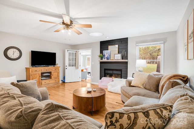 living room with a large fireplace, ceiling fan, and light hardwood / wood-style flooring