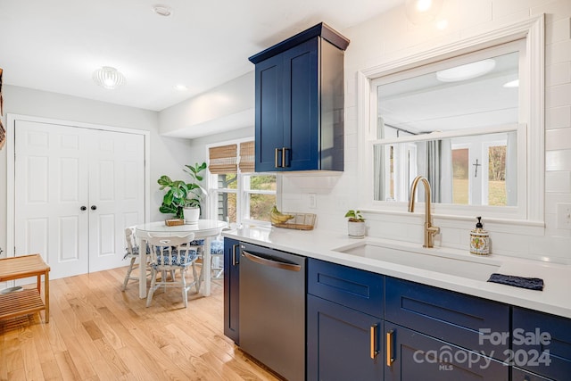 kitchen featuring light hardwood / wood-style floors, sink, blue cabinetry, dishwasher, and decorative backsplash