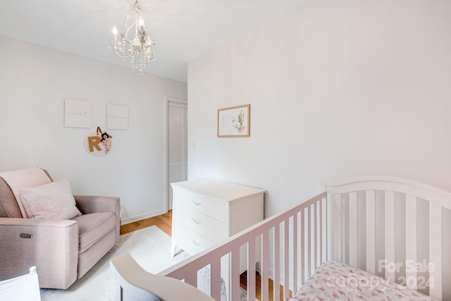 bedroom with a chandelier, light wood-type flooring, and a nursery area