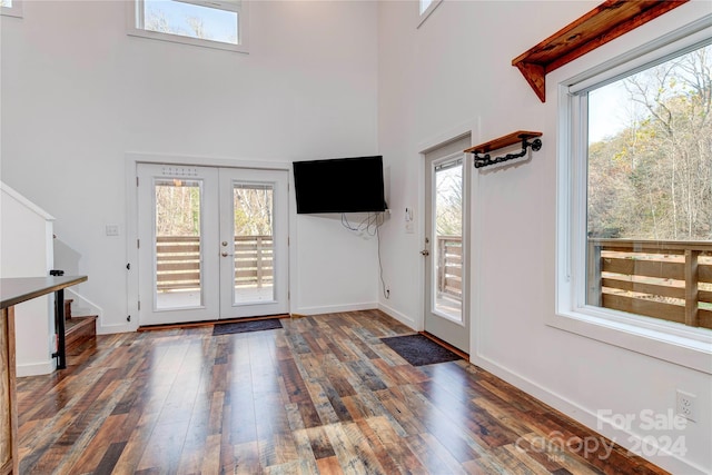 entryway with dark wood-type flooring, a wealth of natural light, french doors, and a high ceiling